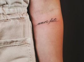 Маленькая тату "amor fati" на руке, символ принятия судьбы и любви, выполнена в элегантном стиле. Татуировка "amor fati" на руке, символ судьбы и любви.