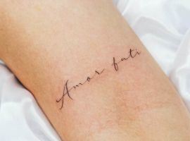 Маленьке тату "Amor Fati" на руці, виконане тонким шрифтом, символізує прийняття долі та життєвий філософський підхід. Тату "Amor Fati" на руці, тонкий шрифт, символізує прийняття долі.