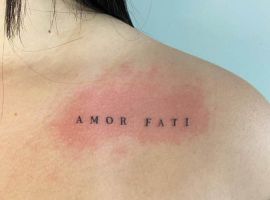 Малюнок татуювання "Amor Fati" на плечі, розташоване на шкірі з природним освітленням, символізує прийняття долі та життєвий філософський підхід. Татуювання "Amor Fati" на плечі, чорний шрифт, мінімалістичний дизайн.