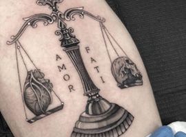 Татуювання "Амор Фаті" з балансами та символами, що символізують прийняття долі та життєвий шлях, виконане у стилі реалістичного татуювання. амор фаті татуювання