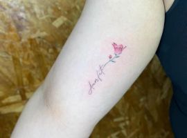 Маленька тату у вигляді квітки з написом "love" на передпліччі, символізує любов і натхнення. Тату у вигляді квітки з написом "love" на руці.