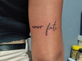 Маленькое тату "amor fati" на руке, символизирующее принятие судьбы и любви к жизни. Тату "amor fati" на руке, символ принятия судьбы и любви.