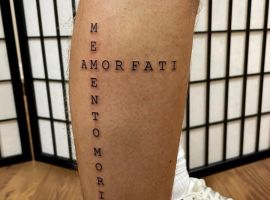 Малюнок татуювання "Amor Fati" на нозі з вертикальним написом "Мир, Любов, Прийняття". Татуювання "Amor Fati" на нозі з текстовим дизайном.