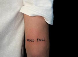Мінімалістичне тату "Amor Fati" на руці, створене в Тату Cалон Альянс, підкреслює філософію прийняття долі. Тату "Amor Fati" на руці, мінімалістичний стиль, тату-салон Альянс.