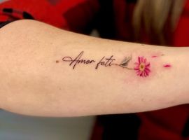 Татуювання "Amor Fati" з квіткою на передпліччі, символ прийняття долі та життєвого шляху. Татуювання "Amor Fati" з квіткою.