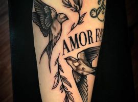 Красива тату-ілюстрація з двома птахами, гілками та написом "AMOR FATI", створена в студії Тату Cалон Альянс. Тату птахів і гілок з написом "AMOR FATI" на руці, символізує прийняття долі та любов до життя.