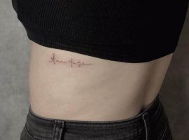 Модель з тату "Amor Fati" на боці, що символізує прийняття долі, зроблене в Тату Cалон Альянс. Тату "Amor Fati" на боці, символ прийняття долі та фатуму, створене в тату-салон Альянс.