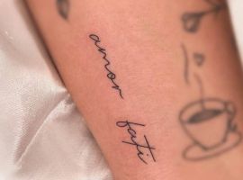Малюнок тату "amour fati" з квітами та чашкою кави на руці, символізує прийняття долі та любов до життя. Тату "amour fati" на руці з квітами та чашкою кави.