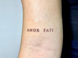 Мінімалістичне тату "Amor Fati" на руці, що символізує прийняття життєвих випробувань. Тату "Amor Fati" на руці, символ прийняття долі та фатуму.