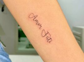 Мінімалістичне тату Love Fati на руці, символ прийняття долі та любові, створене у салоні Тату Cалон Альянс. Тату Love Fati на руці, мінімалістичний стиль, чорний шрифт.