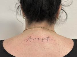 Естетичне тату "Amor Fati" на шиї, що символізує прийняття своєї долі та життєвий філософський підхід. Тату "Amor Fati" на шиї, символ прийняття долі та філософії стоїцизму.