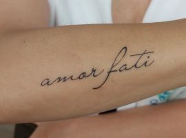 Тату "amor fati" на руці, символ прийняття долі та життєвого шляху, створене майстром у салоні Тату Cалон Альянс. Тату "amor fati" на руці, виконане тонким чорним шрифтом у салоні Тату Cалон Альянс.