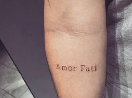 Минималистский тату-арт "Amor Fati" на руке, символ принятия судьбы и жизненных испытаний. Тату "Amor Fati" на предплечье.