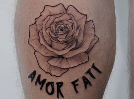 Знімок тату з квіткою та фразою "Amor Fati" у салоні Тату Cалон Альянс. Чорно-біла тату квітка з написом "Amor Fati" на шкірі.