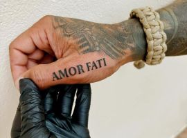 Зображення рука з тату "Amor Fati", що символізує прийняття долі та фаталізм, у тату-салоні Альянс. Тату "Amor Fati" на руці, символ прийняття долі та фаталізму, виконане чорною фарбою.