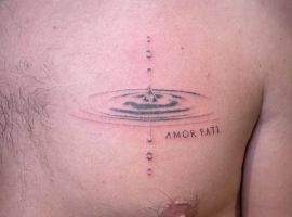 Малюнок "Amor Fati" з краплею води на грудях, символ прийняття долі та філософії життя. Татуювання "Amor Fati" з водяною краплею на грудях чоловіка.