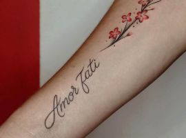 Стильне тату "Amor Fati" з квітами сакури, що символізує прийняття долі та любов до життя. Ідеально для цінителів мистецтва тату. Тату "Amor Fati" з квітами сакури на передпліччі, символ прийняття долі та любові до життя.