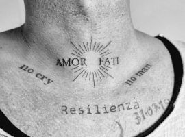 Татуювання "Amor Fati" з сонячним орнаментом і словами "Resilienza" на грудях, символ прийняття долі та внутрішньої сили. Татуювання "Amor Fati" на грудях з сонячним орнаментом і словами "Resilienza".