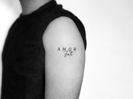 Стильне тату "Amor Fati" на руці, що символізує прийняття своєї долі та любов до життя, створене в салоні Альянс. Тату "Amor Fati" на руці, символ прийняття долі та любові.